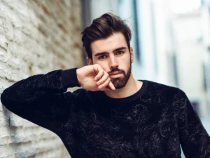 Stylish young man in a black sweater posing outdoors, showcasing natural-looking results from Hair Systems.