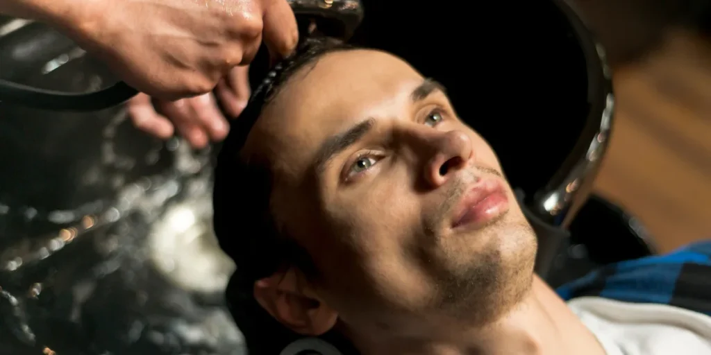 Man receiving a professional hair wash at salon by Hair System Experts in Birmingham.